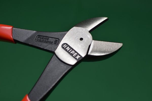 A bolt cutter on a green surface.
