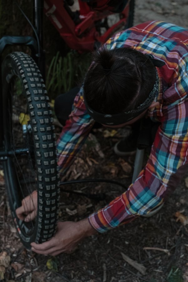 A person out in the woods repairing a flat tire.