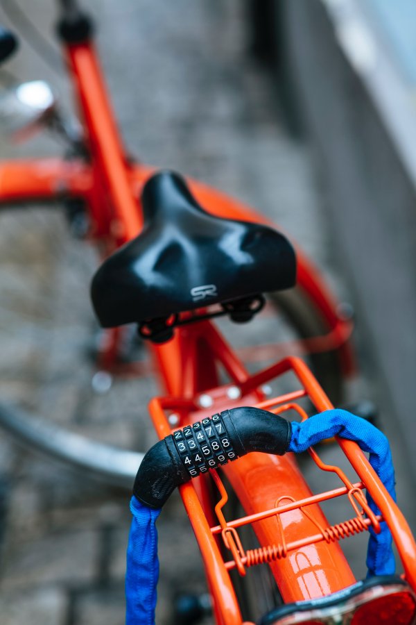 A blue lock securing an orange bike.