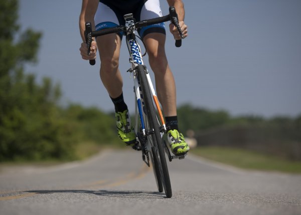 A man riding a bike on a road wearing bike shoes.