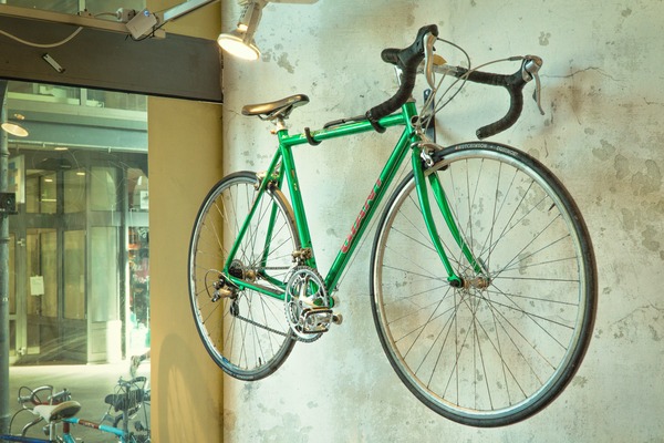 A green bike hung on a wall.