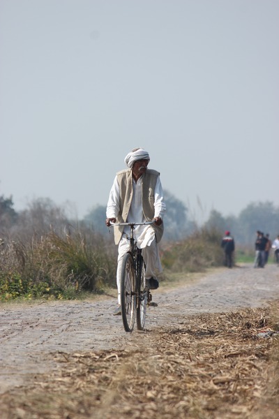 A man riding a bike outdoors, in the hot sun.
