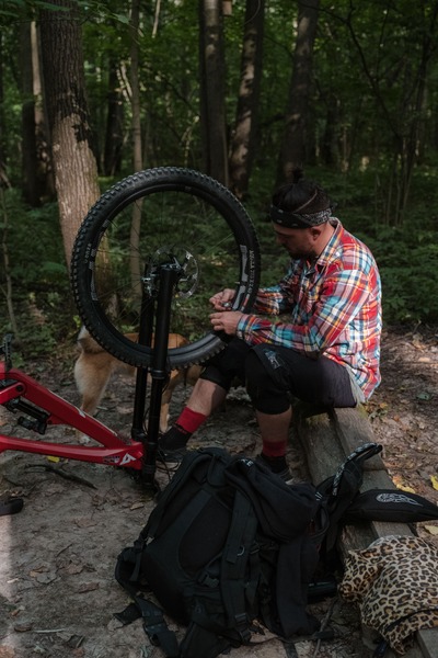 A person out in the woods repairing a bike tire.