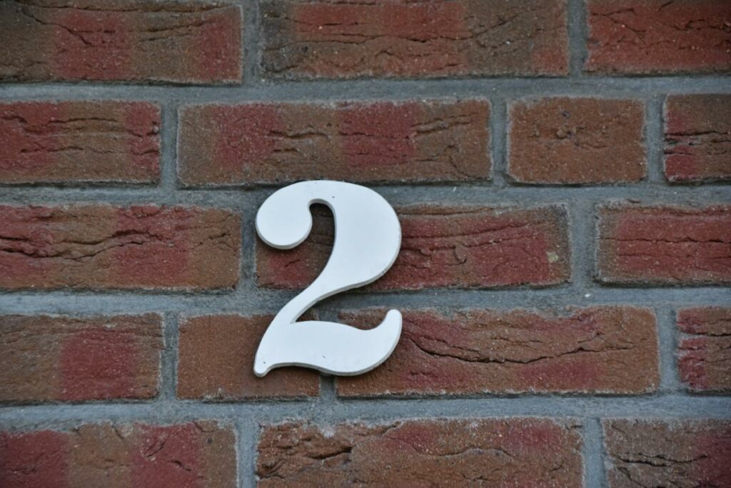 A number 2 house number on a brick wall.
